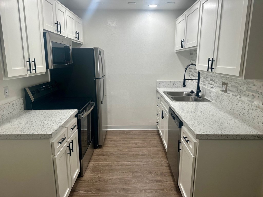 a kitchen with white cabinets and a sink and a refrigerator at Willow Tree Apartments, California, 90505