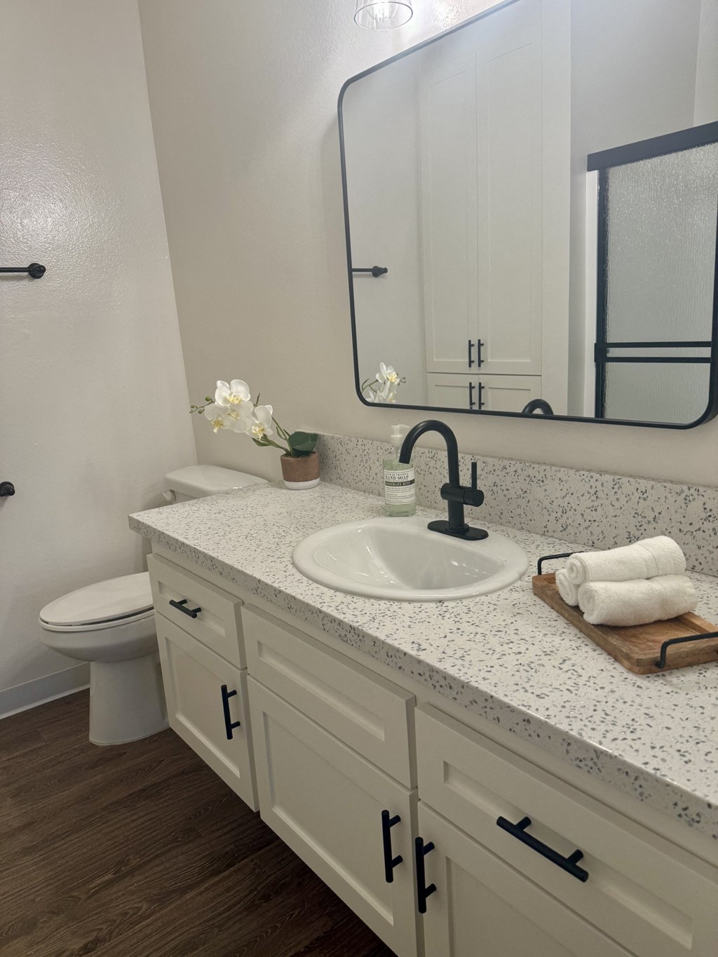 A bathroom with a white toilet and a sink with a black faucet. at Camino de Oro Apartments, Torrance, CA, 90505