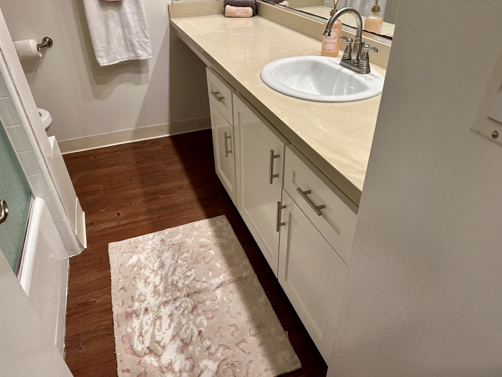 A bathroom with a sink, mirror, and wooden floor at Royal Towers Apartments, Redondo Beach, CA, 90277