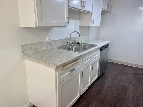 A kitchen with white cabinets and a marble countertop.