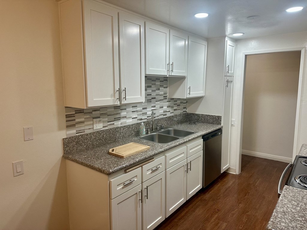 A kitchen with white cabinets and a granite countertop.  at Casa De Oro Apartments, Torrance, 90505