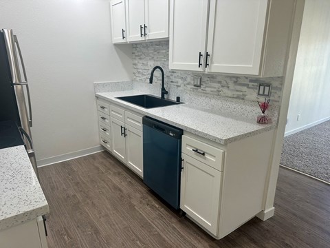 A kitchen with white cabinets and a blue dishwasher.