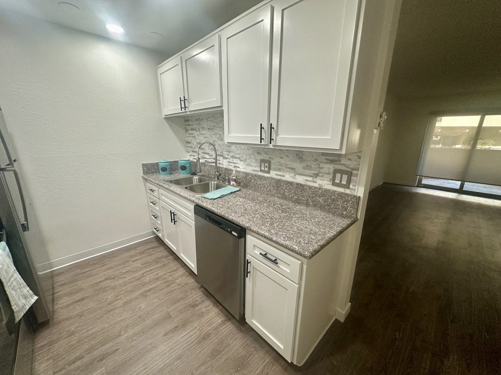 A kitchen with white cabinets and a granite countertop. at Willow Tree Apartments, California, 90505