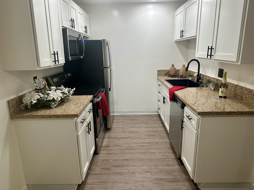 A kitchen with black appliances and white cabinets at Willow Tree Apartments, California, 90505