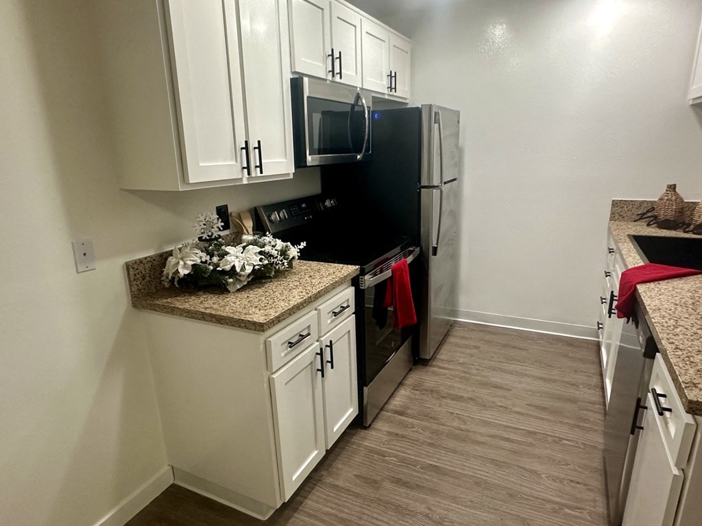 A kitchen with white cabinets and a black fridge at Willow Tree Apartments, California, 90505