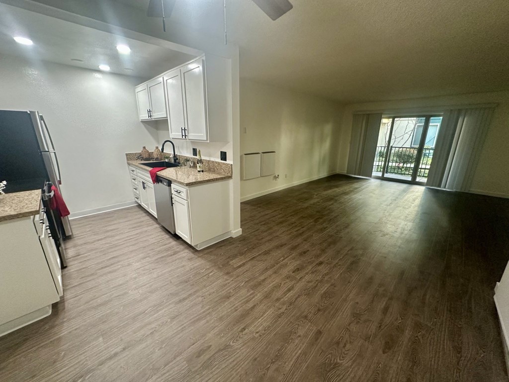 A kitchen with white cabinets and a wooden floor at Willow Tree Apartments, California, 90505