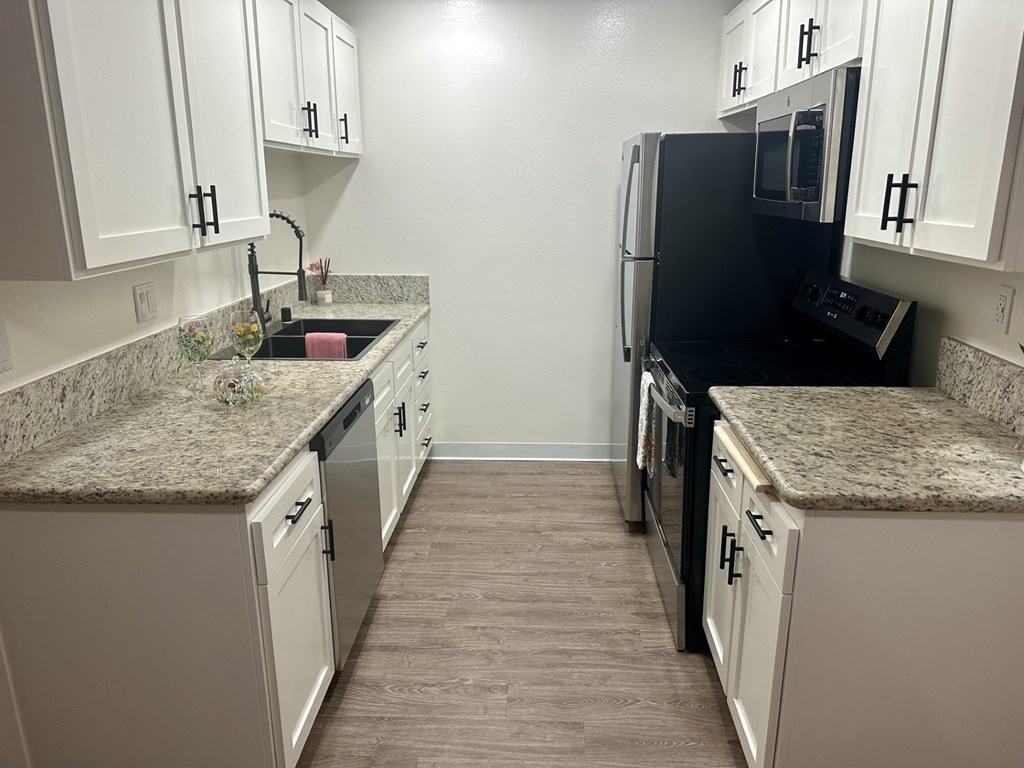 A kitchen with black appliances and white cabinets.