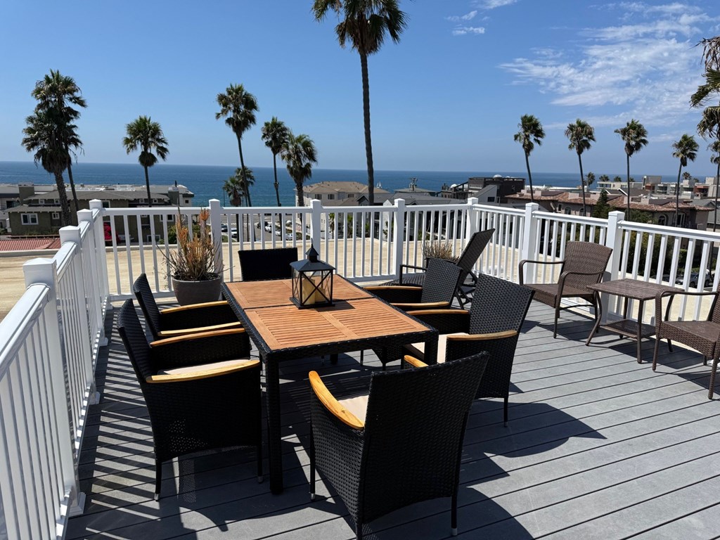 A patio with a table and chairs overlooking the ocean.