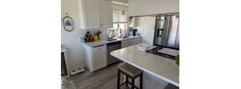 A kitchen with a white countertop and a stainless steel refrigerator.