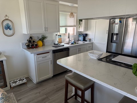 A kitchen with a white countertop and a stainless steel refrigerator.