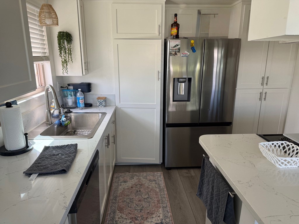 A kitchen with a refrigerator, sink, and cabinets.