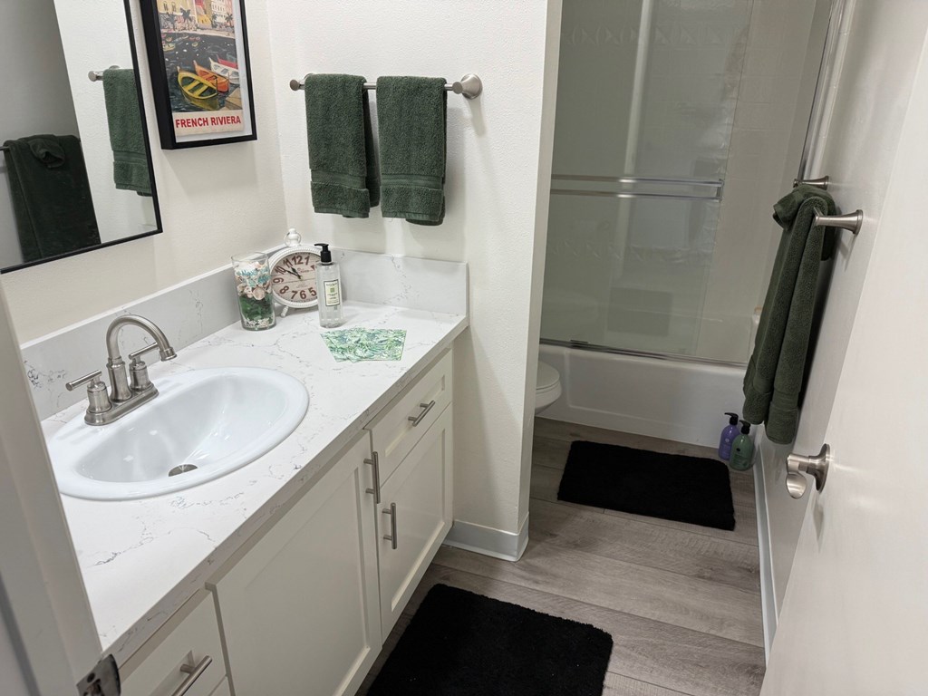 A bathroom with a white sink and a glass shower door.