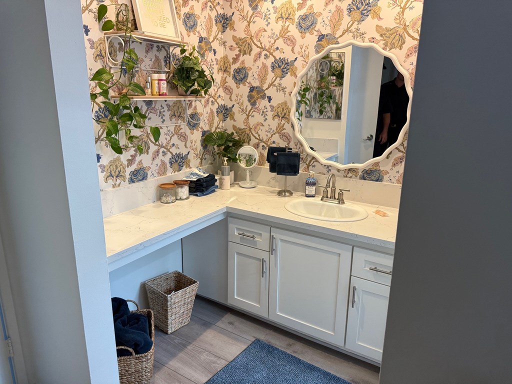A bathroom with a floral wallpaper and a white vanity.