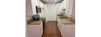A kitchen with white cabinets and brown countertops.