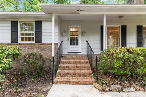 A white house with a black front door and steps.