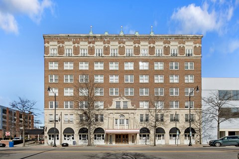 A large brown building with a red awning sits in front of a blue sky.