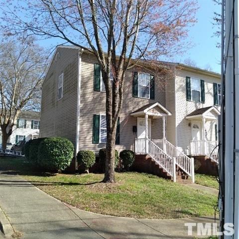 A two-story house with a front porch and a tree in front.