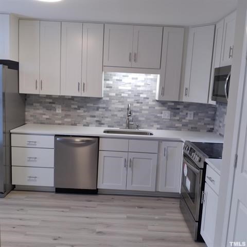 A kitchen with white cabinets and a grey backsplash.
