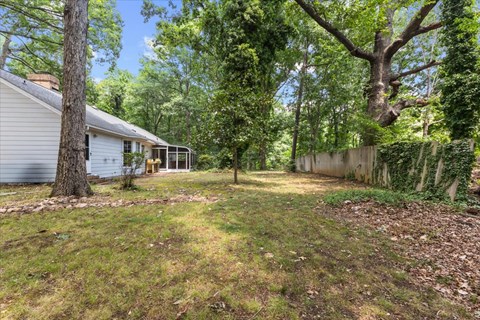 A backyard with a house, trees, and a fence.