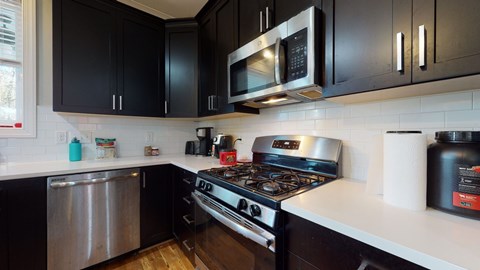 A modern kitchen with black cabinets and stainless steel appliances.