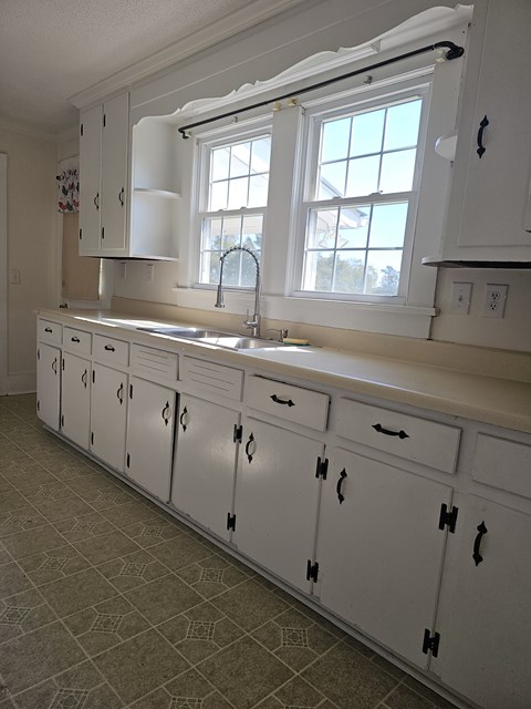 A kitchen with white cabinets and a window above the sink.