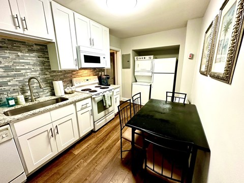A kitchen with a black table and white cabinets.