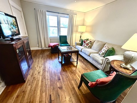 A living room with a green chair and a white couch.