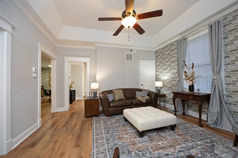A living room with a brown couch and a white ottoman.