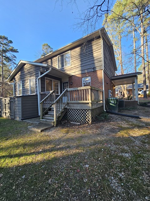 A house with a grey and brown exterior and a wooden deck.