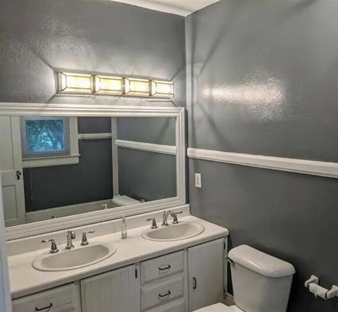 A bathroom with two sinks and a toilet.