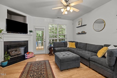 A living room with a grey couch and a fireplace.