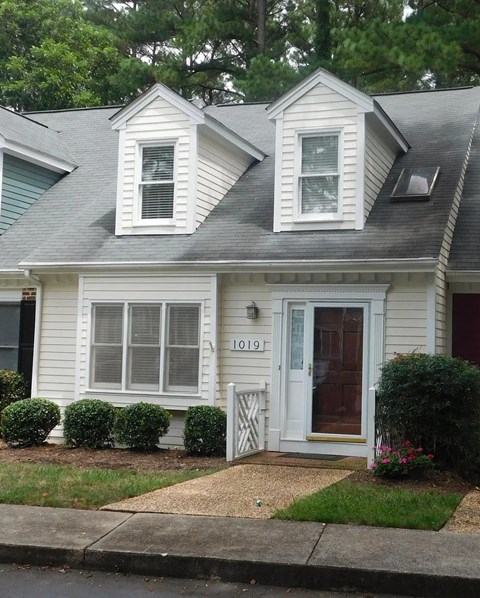 A white house with a grey roof and a black door.