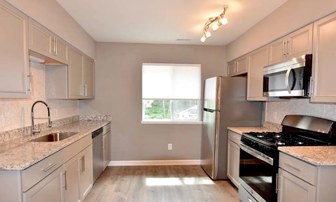 A kitchen with a sink, refrigerator, and stove.