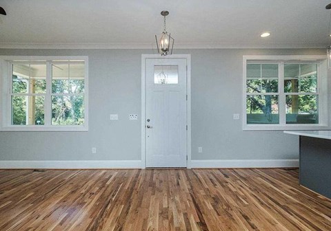 A room with a white door and wooden flooring.