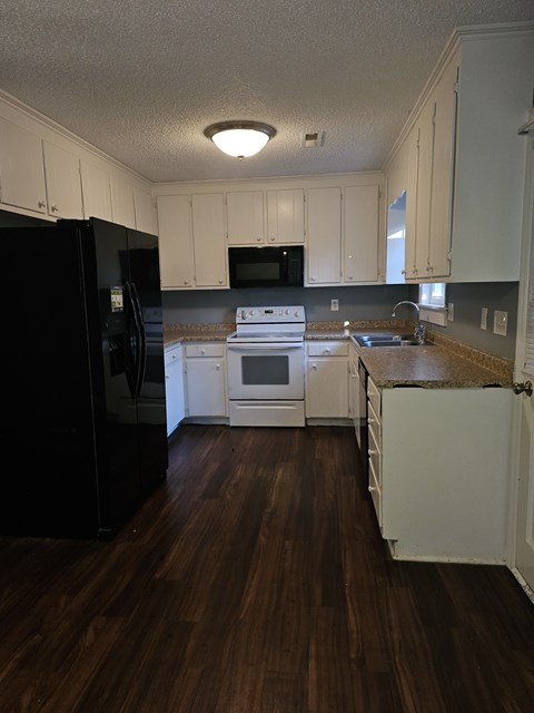 A kitchen with black appliances and white cabinets.