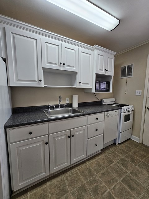 A kitchen with white cabinets and a black countertop.