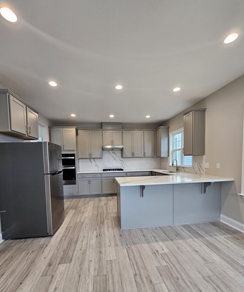 A modern kitchen with a refrigerator, cabinets, and a countertop.