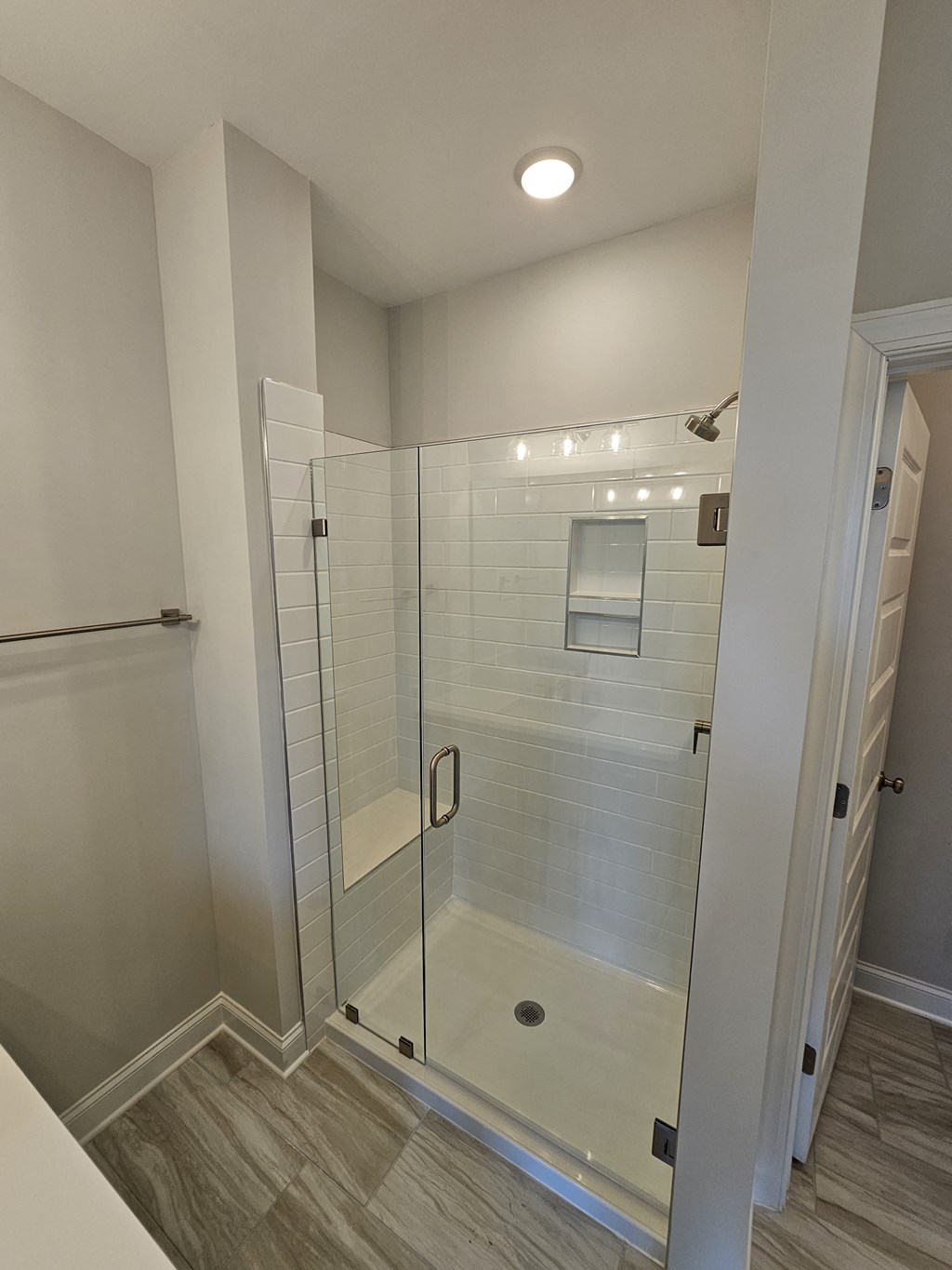 a large shower with a glass door in a renovated bathroom