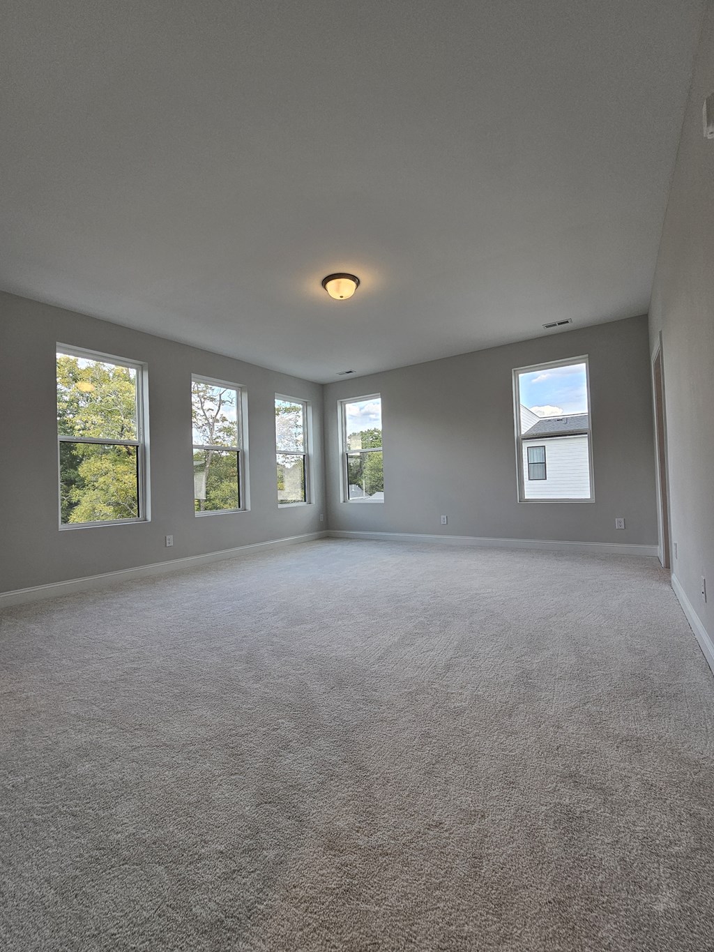 an empty living room with windows and carpeting