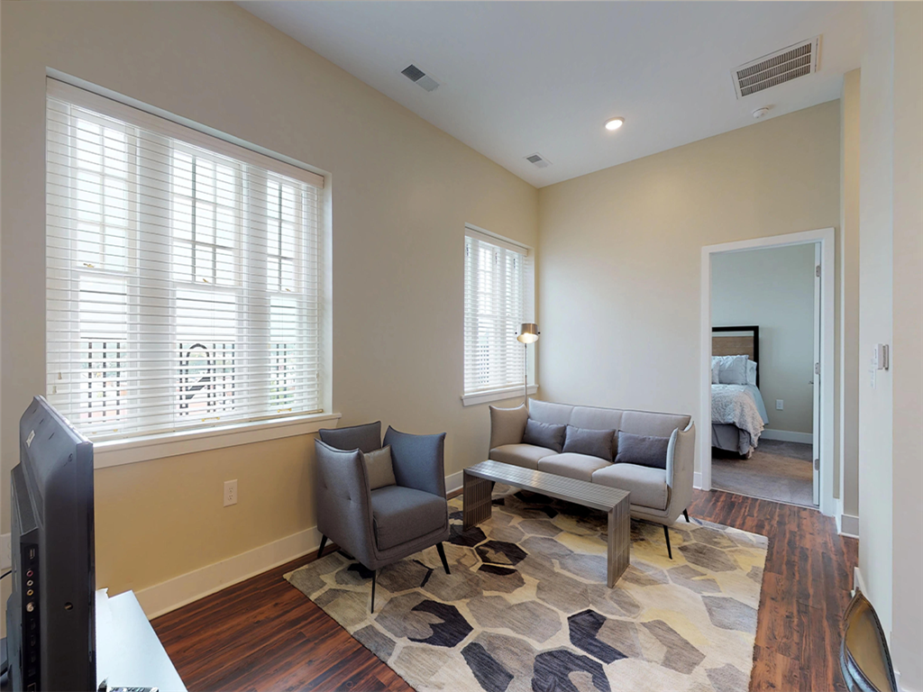 A living room with a grey couch, two chairs, and a rug.