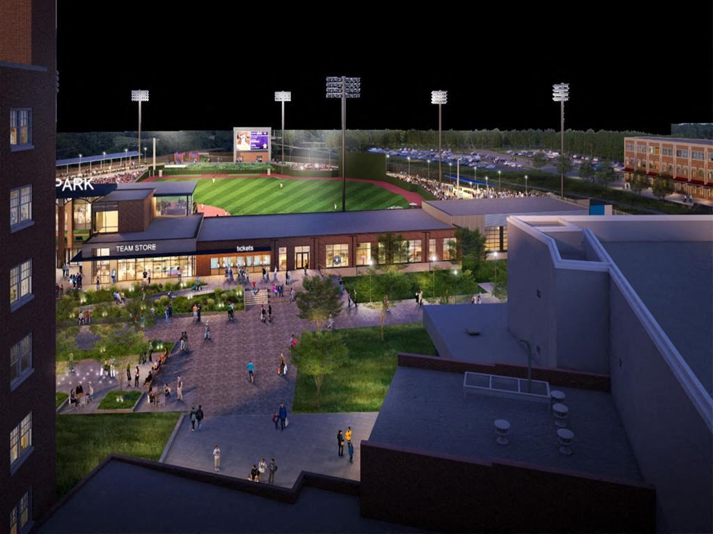 A stadium with a green field and a scoreboard at night.