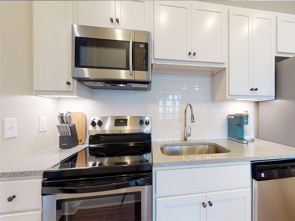 A modern kitchen with white cabinets and stainless steel appliances.
