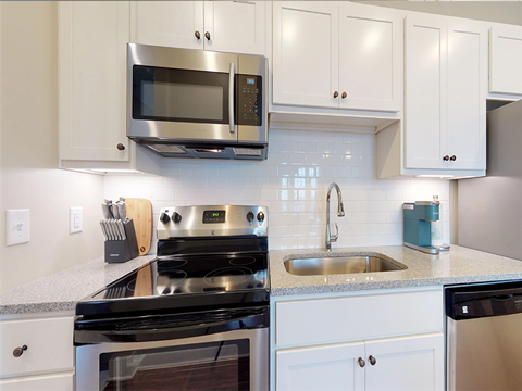A modern kitchen with white cabinets and stainless steel appliances.
