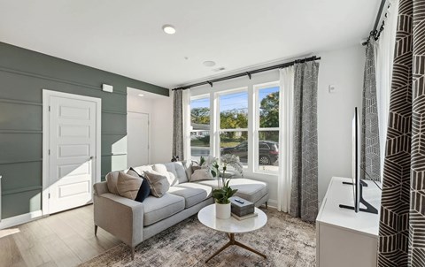 A living room with a grey couch and a coffee table in front of a window.