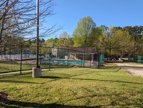A park with a fenced-in area and a building in the background.