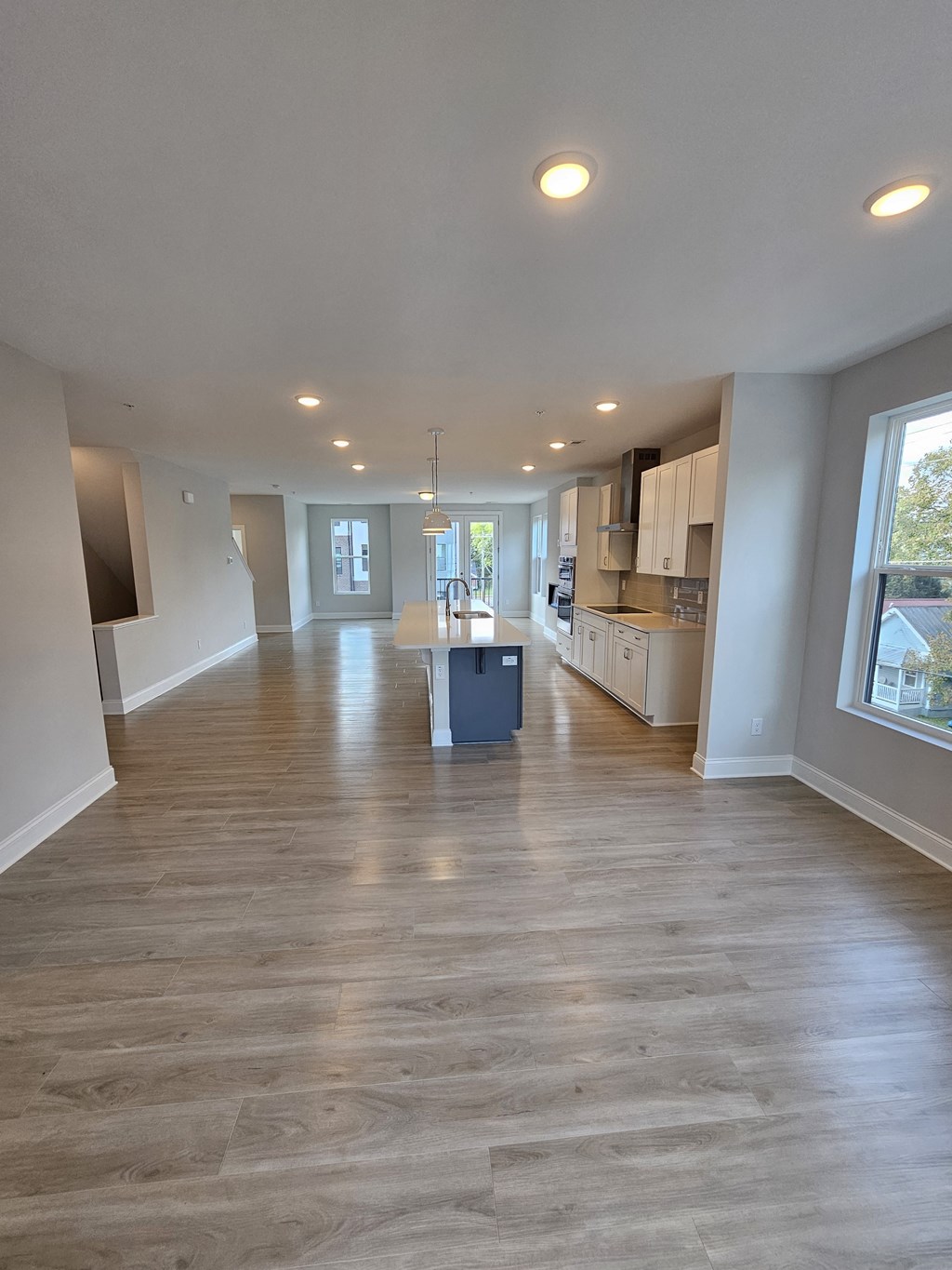 an empty living room and kitchen with wood flooring