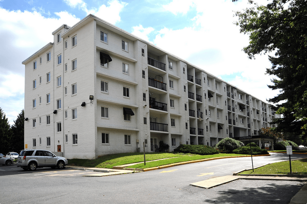 a large white apartment building with cars parked outside