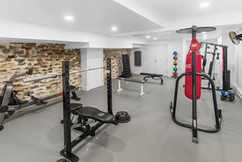 A home gym with a variety of equipment including a squat rack, bench, and a punching bag.