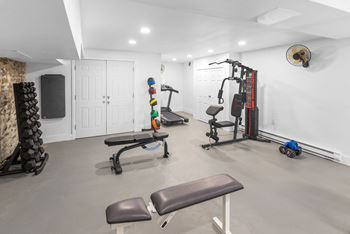 A home gym with a variety of equipment including a treadmill, weights, and a bench.