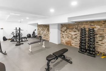 A gym with a variety of equipment including weights and a bench.